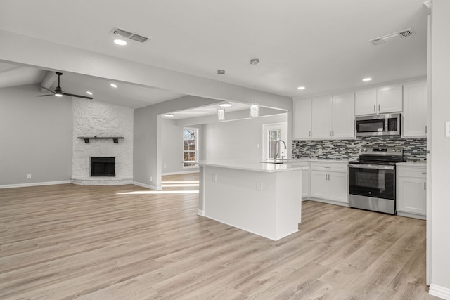 kitchen with a fireplace, white cabinetry, stainless steel appliances, and hanging light fixtures