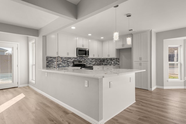 kitchen featuring stainless steel appliances, decorative light fixtures, light wood-type flooring, light stone countertops, and white cabinets