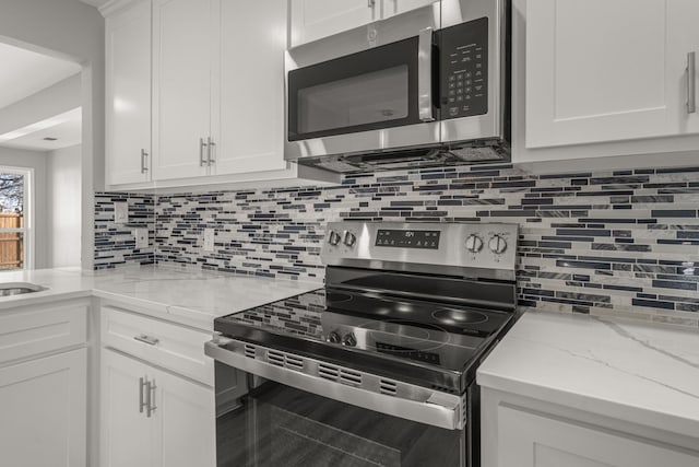 kitchen with light stone counters, white cabinets, stainless steel appliances, and tasteful backsplash