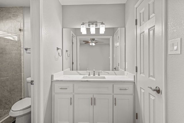 bathroom featuring toilet, ceiling fan, a tile shower, and vanity