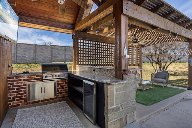 view of patio with ceiling fan, a grill, a wet bar, and exterior kitchen