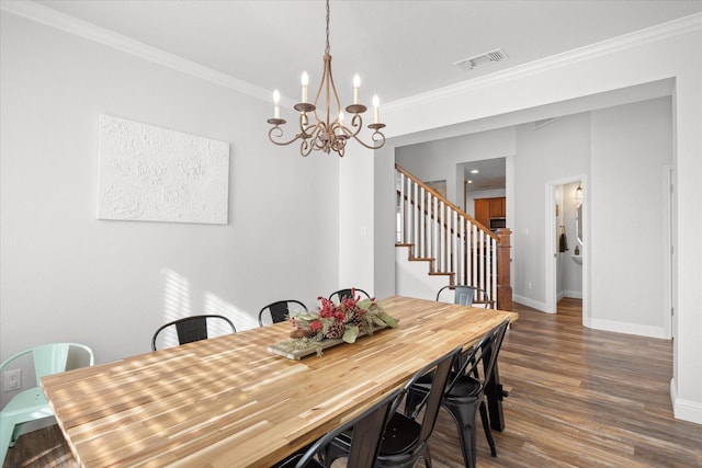 dining room with dark hardwood / wood-style flooring, ornamental molding, and a chandelier