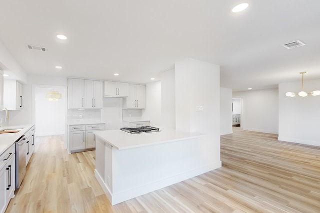 kitchen featuring pendant lighting, white cabinetry, decorative backsplash, sink, and stainless steel dishwasher