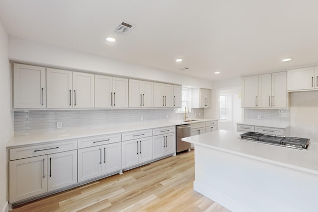 kitchen featuring light wood-type flooring, appliances with stainless steel finishes, backsplash, and sink