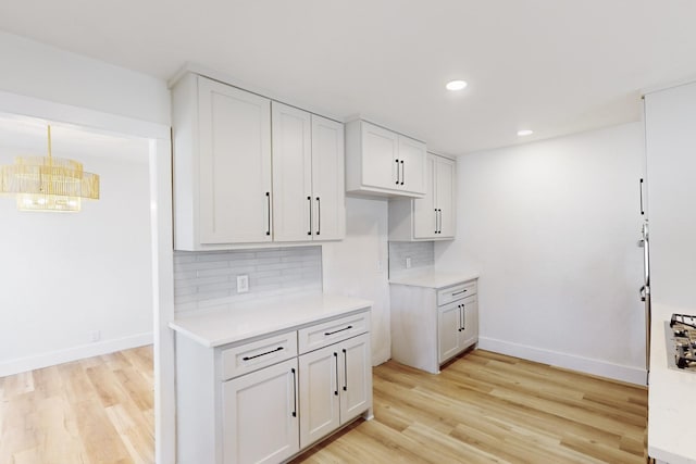 kitchen with white cabinetry, decorative backsplash, light hardwood / wood-style floors, and pendant lighting