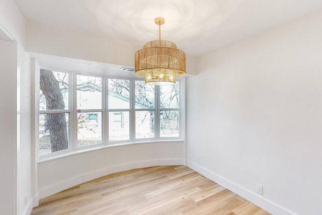 unfurnished dining area featuring a chandelier and hardwood / wood-style flooring