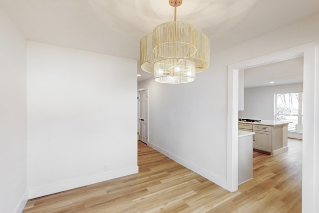 unfurnished dining area featuring light wood-type flooring and a notable chandelier