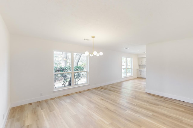 unfurnished room with an inviting chandelier and light hardwood / wood-style floors