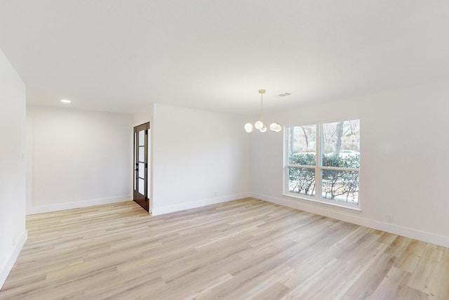 spare room with light hardwood / wood-style flooring and a chandelier