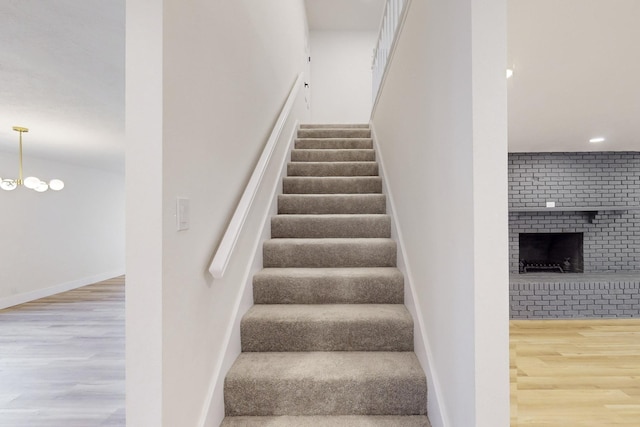 staircase with a fireplace and wood-type flooring