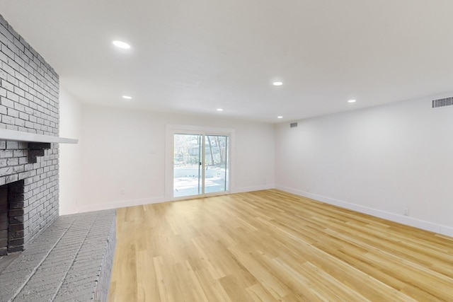 unfurnished living room featuring a brick fireplace and light wood-type flooring