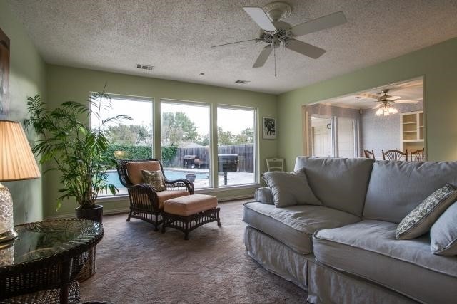 living room featuring ceiling fan, carpet, and a textured ceiling