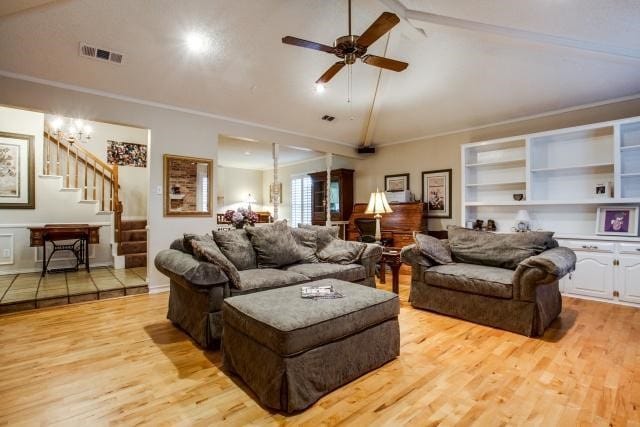 living room with ceiling fan with notable chandelier, light hardwood / wood-style floors, built in features, ornamental molding, and vaulted ceiling