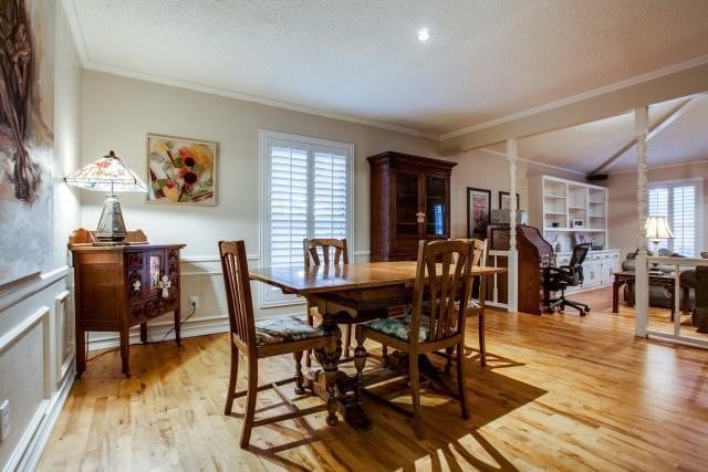 dining area with plenty of natural light, a textured ceiling, light hardwood / wood-style flooring, and ornamental molding