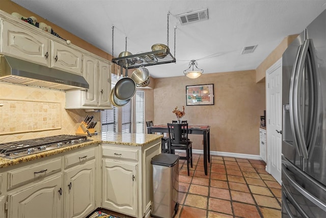 kitchen featuring kitchen peninsula, cream cabinetry, backsplash, and stainless steel appliances