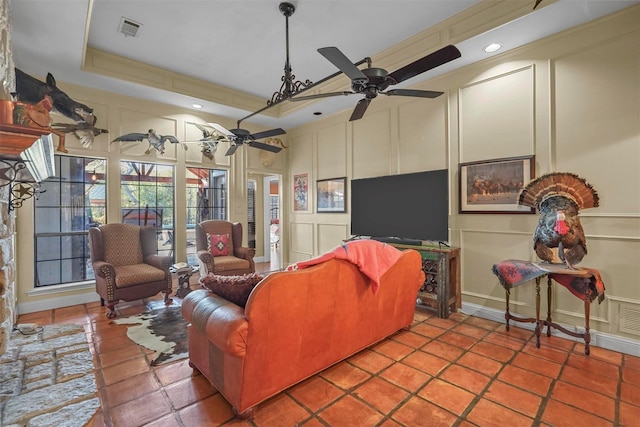 tiled living room featuring a raised ceiling and ceiling fan