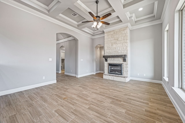 unfurnished living room with ceiling fan, arched walkways, a fireplace, visible vents, and light wood-type flooring