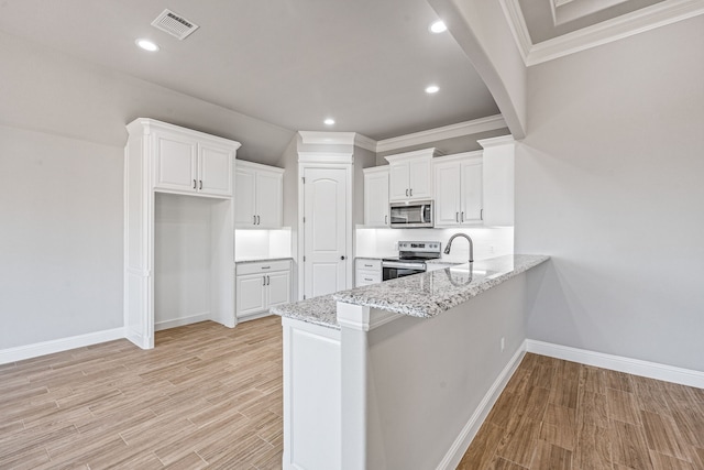 kitchen featuring light wood finished floors, stainless steel appliances, white cabinets, light stone countertops, and a peninsula