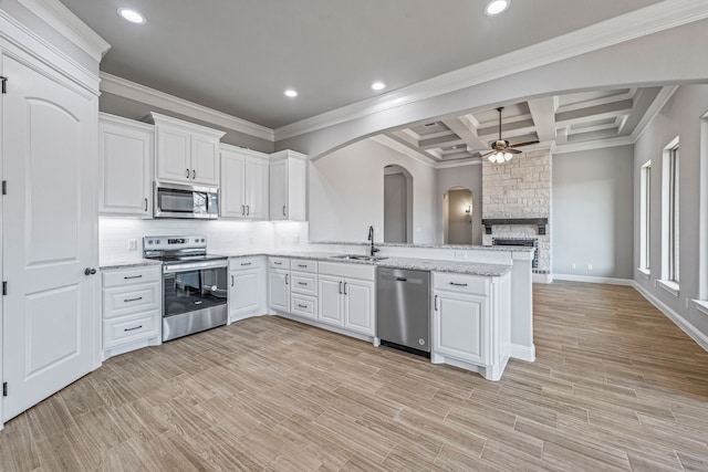 kitchen with arched walkways, appliances with stainless steel finishes, a peninsula, a sink, and backsplash