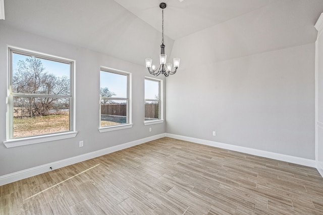 unfurnished room featuring lofted ceiling, an inviting chandelier, baseboards, and light wood-style floors