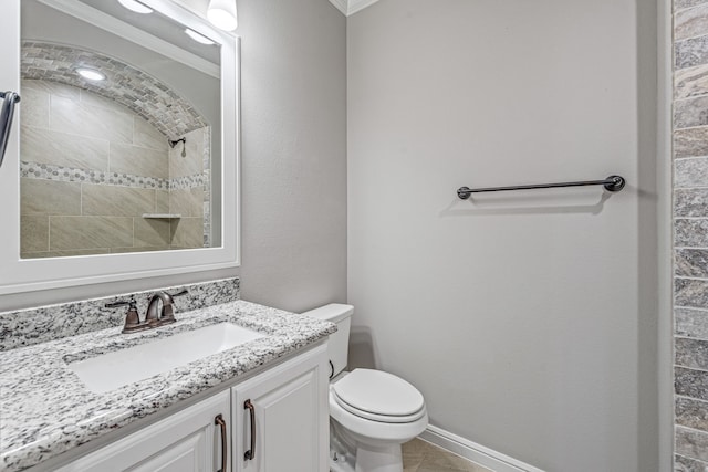 bathroom featuring baseboards, toilet, a tile shower, crown molding, and vanity