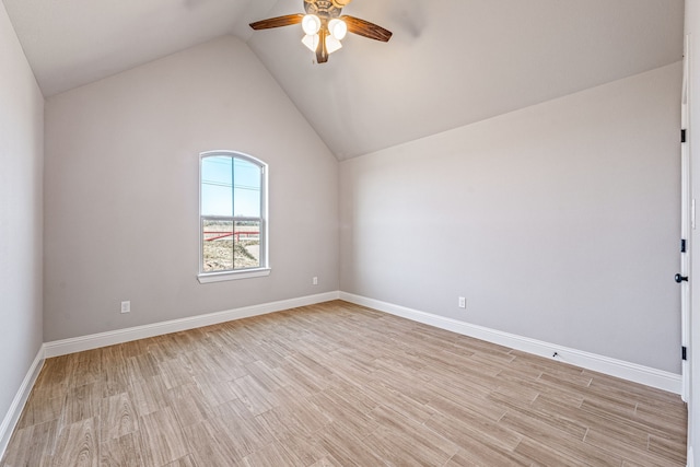 empty room with a ceiling fan, baseboards, vaulted ceiling, and light wood finished floors