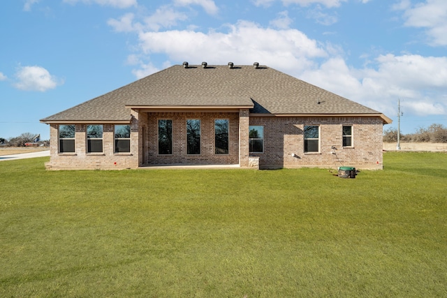 rear view of property with brick siding, a lawn, and a shingled roof