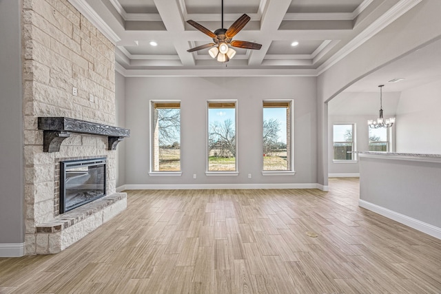 unfurnished living room with baseboards, wood finished floors, crown molding, a fireplace, and ceiling fan with notable chandelier