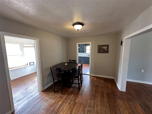 dining space with dark wood-type flooring, a textured ceiling, and a wealth of natural light