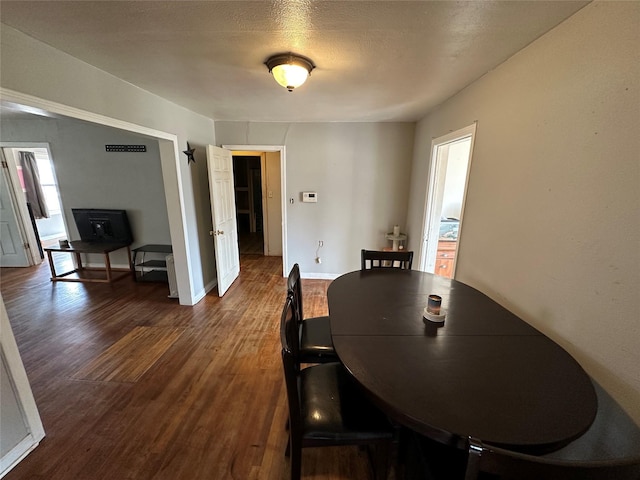 dining room featuring a textured ceiling and dark hardwood / wood-style flooring