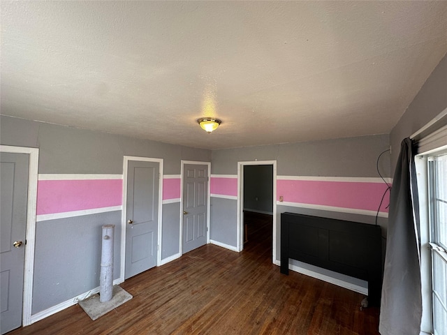 unfurnished bedroom featuring a textured ceiling and dark hardwood / wood-style flooring