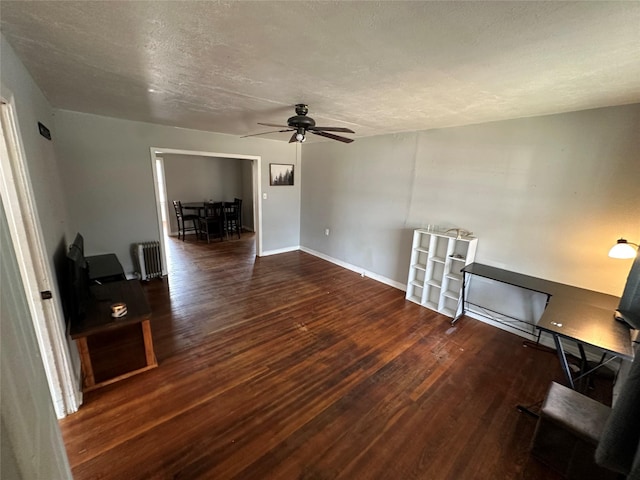 unfurnished living room with ceiling fan, dark hardwood / wood-style floors, radiator heating unit, and a textured ceiling