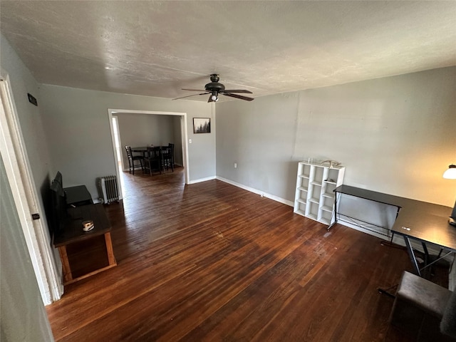 unfurnished living room with radiator, ceiling fan, and dark hardwood / wood-style floors