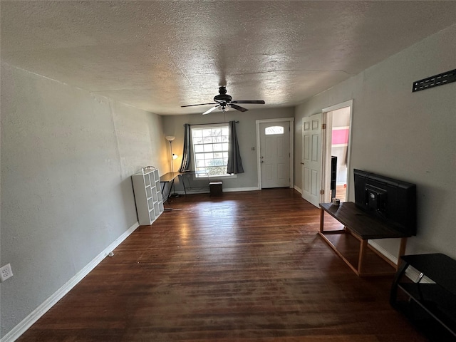 unfurnished living room featuring a textured ceiling, dark wood-type flooring, and ceiling fan