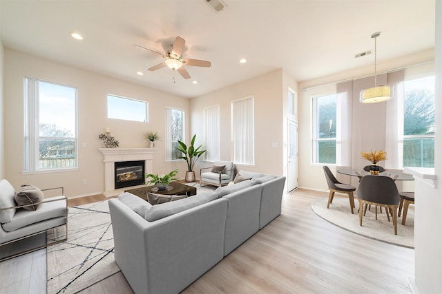 living room with light wood-type flooring, ceiling fan, and a wealth of natural light