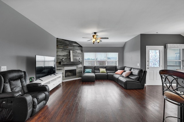 living room with a tiled fireplace, dark hardwood / wood-style flooring, vaulted ceiling, and ceiling fan