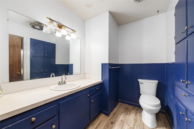 bathroom featuring wood-type flooring, a textured ceiling, toilet, and vanity