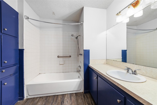 bathroom with a textured ceiling, tiled shower / bath, hardwood / wood-style flooring, and vanity