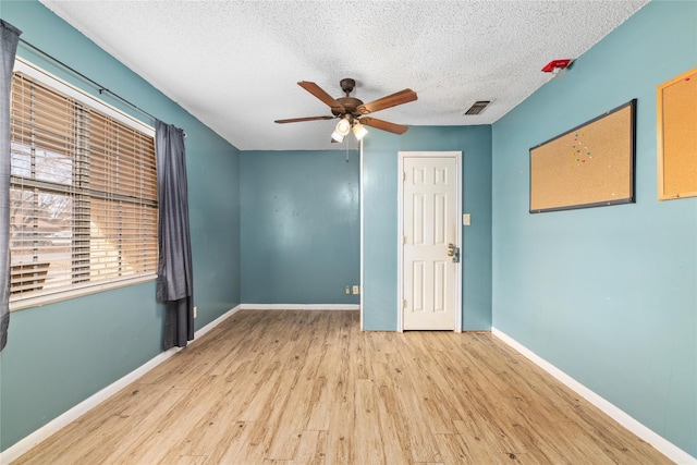 spare room with a textured ceiling, ceiling fan, and light hardwood / wood-style flooring