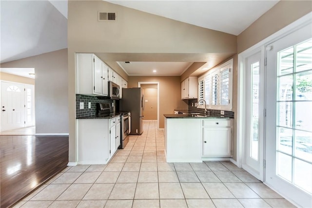 kitchen featuring lofted ceiling, light tile patterned floors, stainless steel appliances, and white cabinetry