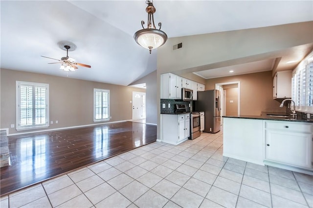 kitchen with pendant lighting, decorative backsplash, sink, white cabinetry, and appliances with stainless steel finishes