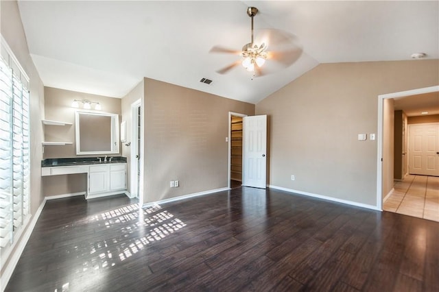 interior space featuring ceiling fan, dark wood-type flooring, built in shelves, and lofted ceiling