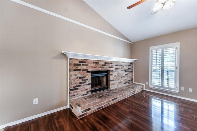 unfurnished living room with ceiling fan, vaulted ceiling, a brick fireplace, and wood-type flooring