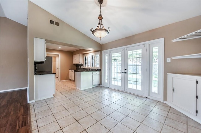 kitchen featuring pendant lighting, white cabinets, vaulted ceiling, french doors, and light tile patterned flooring