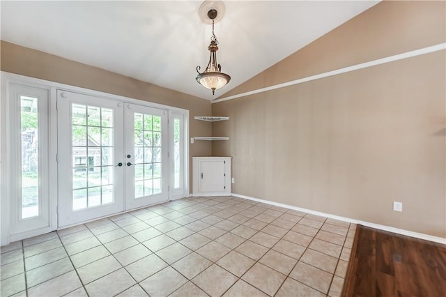 tiled spare room featuring vaulted ceiling, a healthy amount of sunlight, french doors, and built in shelves