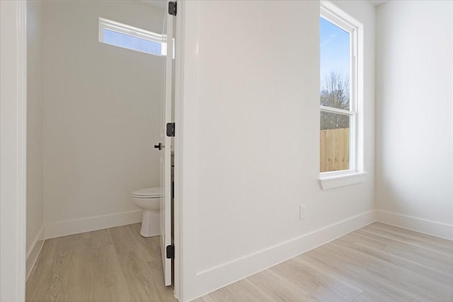 bathroom with toilet, a wealth of natural light, and hardwood / wood-style flooring