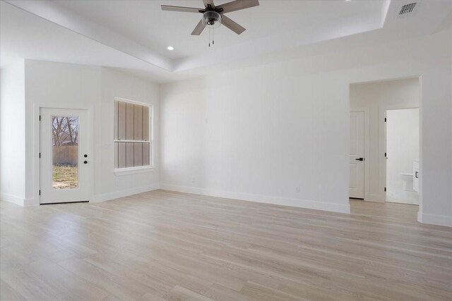 spare room featuring light wood-type flooring, ceiling fan, and a tray ceiling