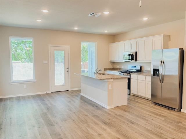 kitchen featuring a center island with sink, appliances with stainless steel finishes, white cabinets, light hardwood / wood-style flooring, and sink