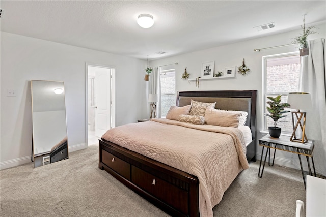 bedroom with light carpet and connected bathroom