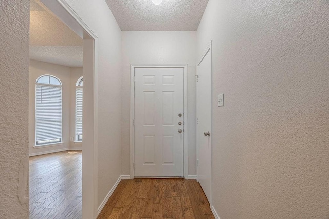 doorway to outside with wood-type flooring and a textured ceiling